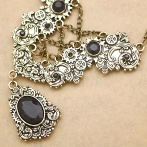 Close-up detail of steampunk necklace showing bronze-toned layered chain construction, oval black gemstone, and ornate filigree pendant design