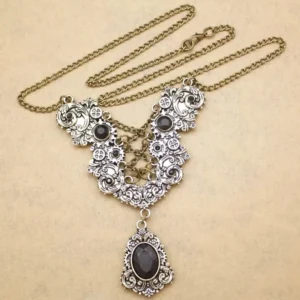Steampunk vintage necklace with silver-toned filigree chain and black teardrop gemstone pendant, flat lay photography showcasing intricate metalwork detail