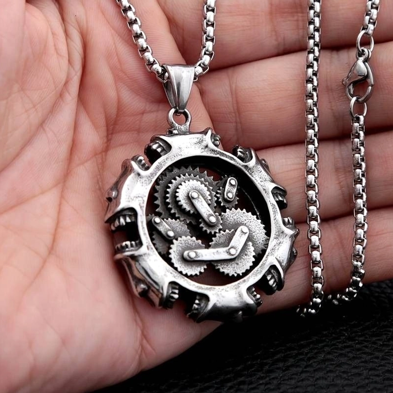 Steampunk gear pendant necklace held in human palm, showing polished silver metal, working gear mechanism interior, and wheat-link chain detail in overhead view