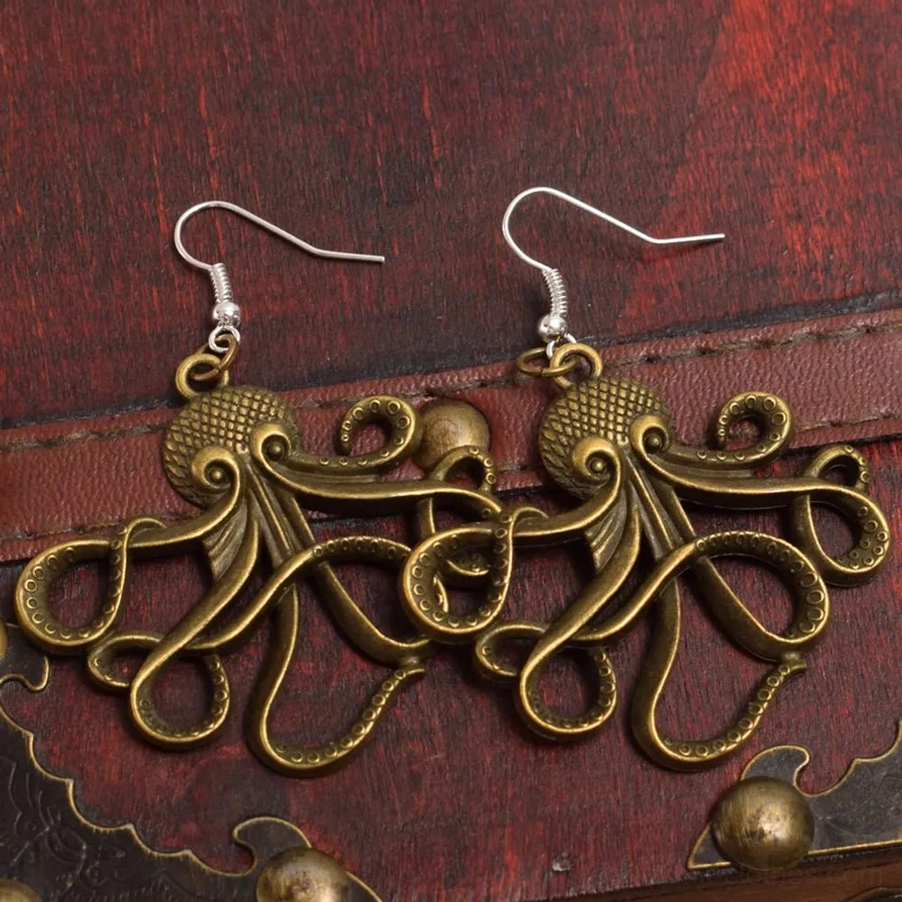 Steampunk octopus drop earrings with antique bronze tentacles displayed on vintage wooden treasure chest with leather trim, showing intricate carved curled tentacles and silver ear hooks