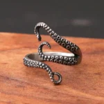 Steampunk octopus tentacle ring with detailed suction cup texture, antique silver finish displayed on light wooden surface