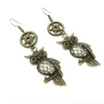Steampunk owl dangle earrings with bronze metal, hollow-carved design, and gear charm details on white background