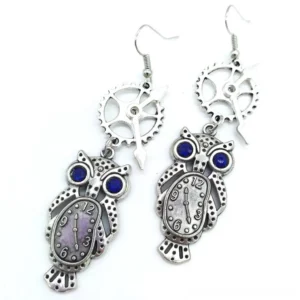 Steampunk owl pendant earrings featuring antique silver metal, sapphire-blue gem eyes, purple-toned clock faces with unique hand designs - flat lay display