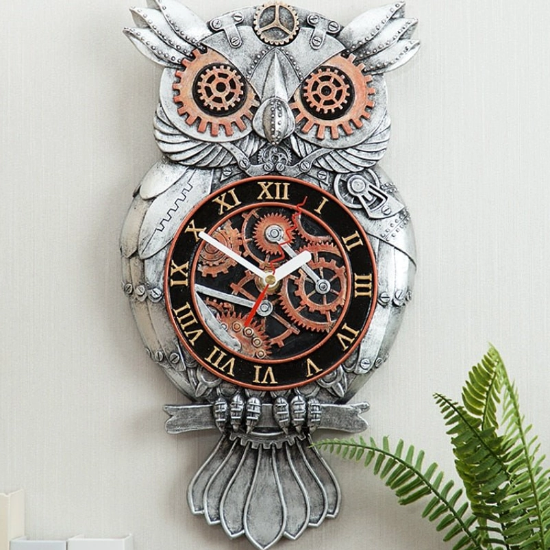 Steampunk owl wall clock with silver resin body and copper gear accents displayed on indoor fern background, featuring Roman numeral dial and intricate vintage-inspired mechanical details