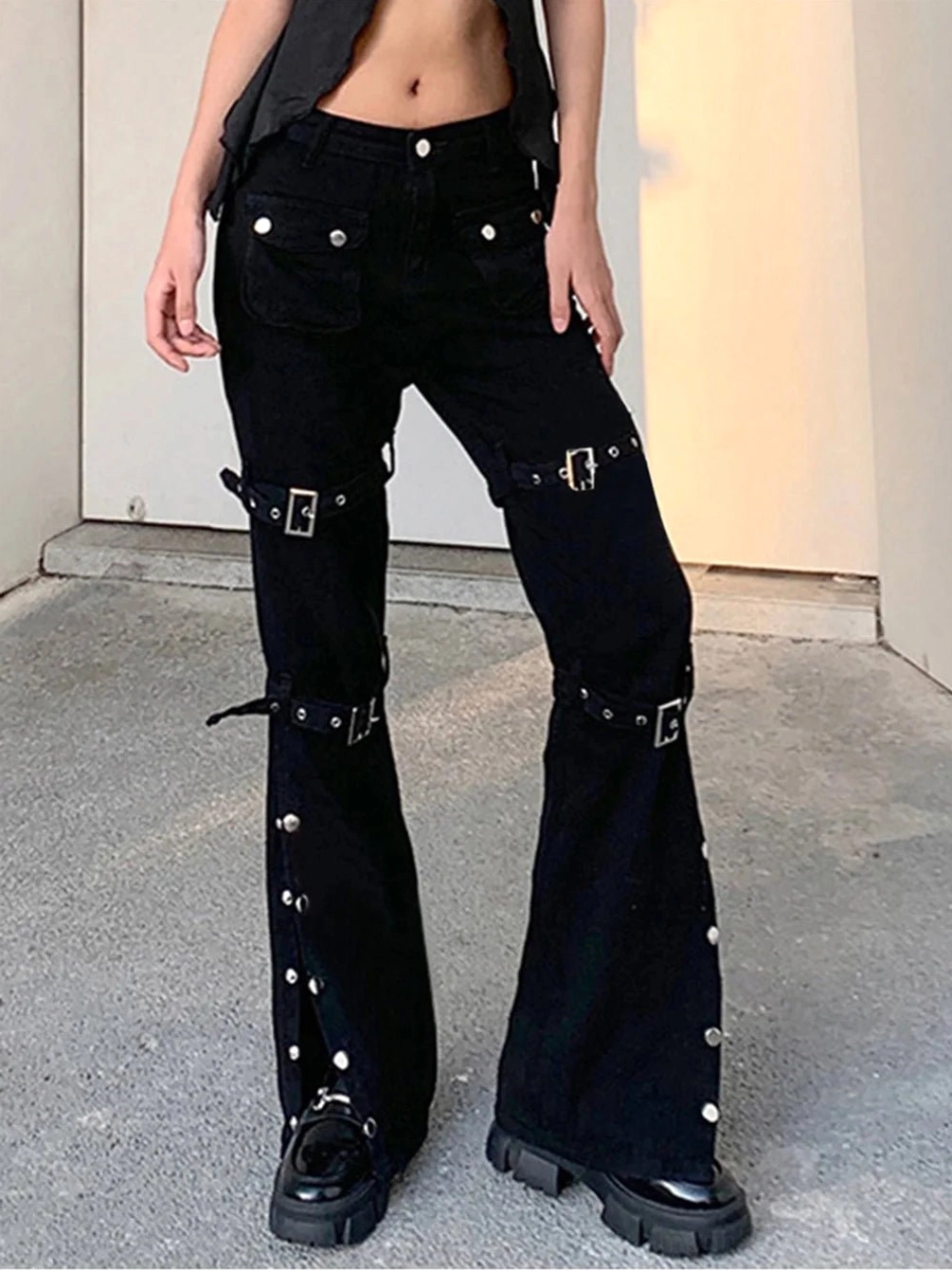 Steampunk buckle-strap flared trousers detail shot showing metal studs, D-ring hardware, and gothic buckle accents on cargo pants
