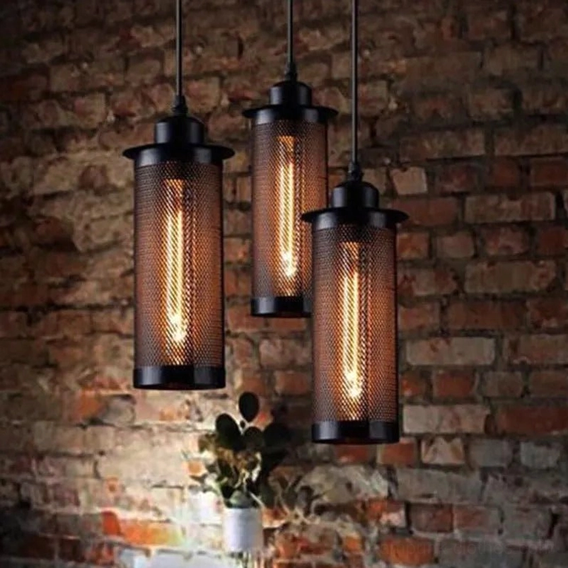 3-unit industrial steampunk pendant light set installed in loft interior against brick wall, dark cylindrical metal mesh shades with visible Edison filament bulbs, side eye-level view