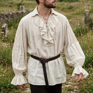 Steampunk pirate shirt with ruffled lace collar and bell sleeves worn by bearded man in natural beige linen, left three-quarter front view on grassy outdoor background