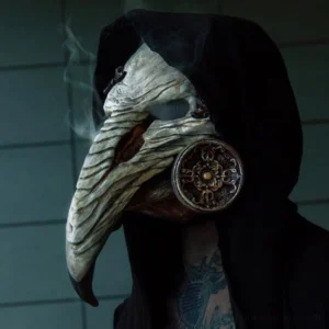 Steampunk plague doctor mask worn by male model in black hooded robe, left side close-up showcasing textured bone-like beak and ornate metal gas filter with atmospheric smoke effect