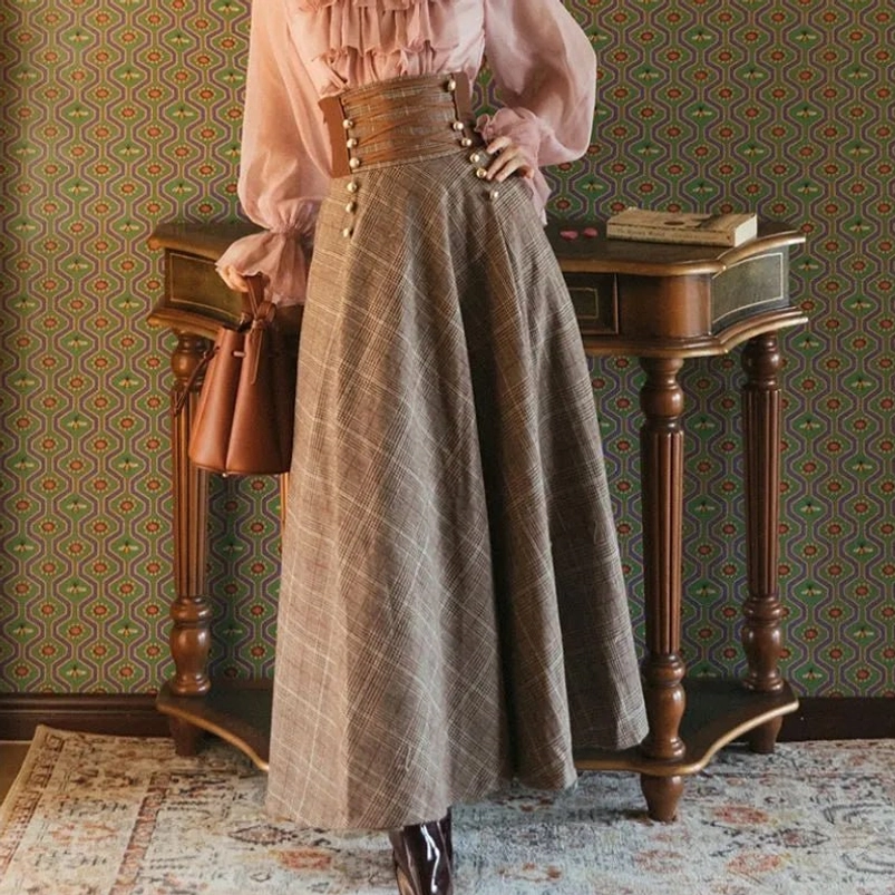 High-waist brown plaid steampunk maxi skirt with leather corset waist panel, front three-quarter view on model wearing pink ruffled blouse