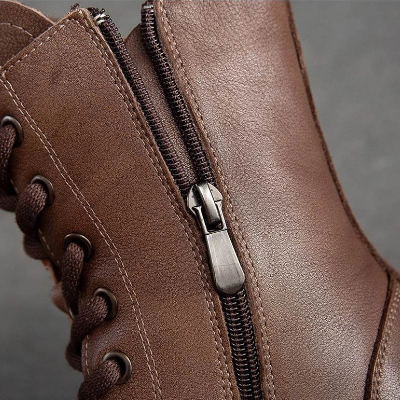 Close-up detail shot of steampunk platform boots showcasing genuine leather texture, metal side zipper hardware, and precision lace eyelets on studio grey background