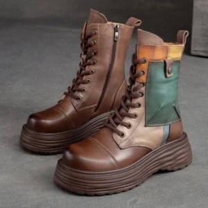 Women's steampunk platform combat boots with genuine leather color-block upper and thick ridged sole, front three-quarter view showcasing metal side zipper and lace eyelet details