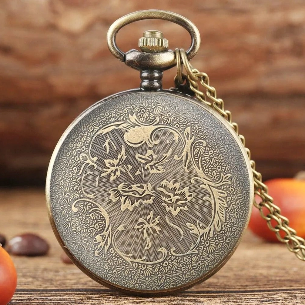 Vintage steampunk pocket watch rear cover showing full floral engraved patterns and antique bronze finish detail on wooden table background