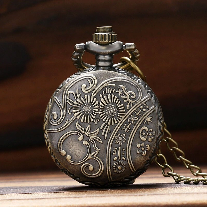 Back of floral steampunk pocket watch with embossed scroll pattern and attached chain