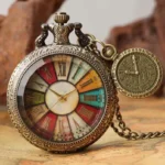 Steampunk pocket watch with bronze metal case and colorful Roman numeral dial, featuring carved details and attached charm pendant on vintage map background