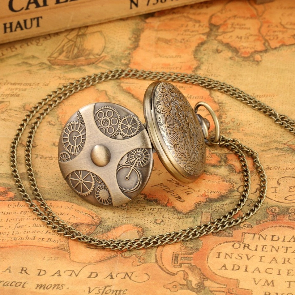 Opened steampunk pocket watch showing both engraved sides and quartz movement on vintage book pages and map