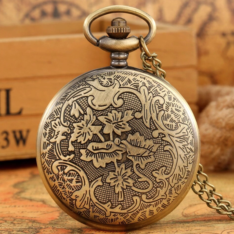 Brass steampunk pocket watch with floral engraved cover and chain on vintage wooden box backdrop