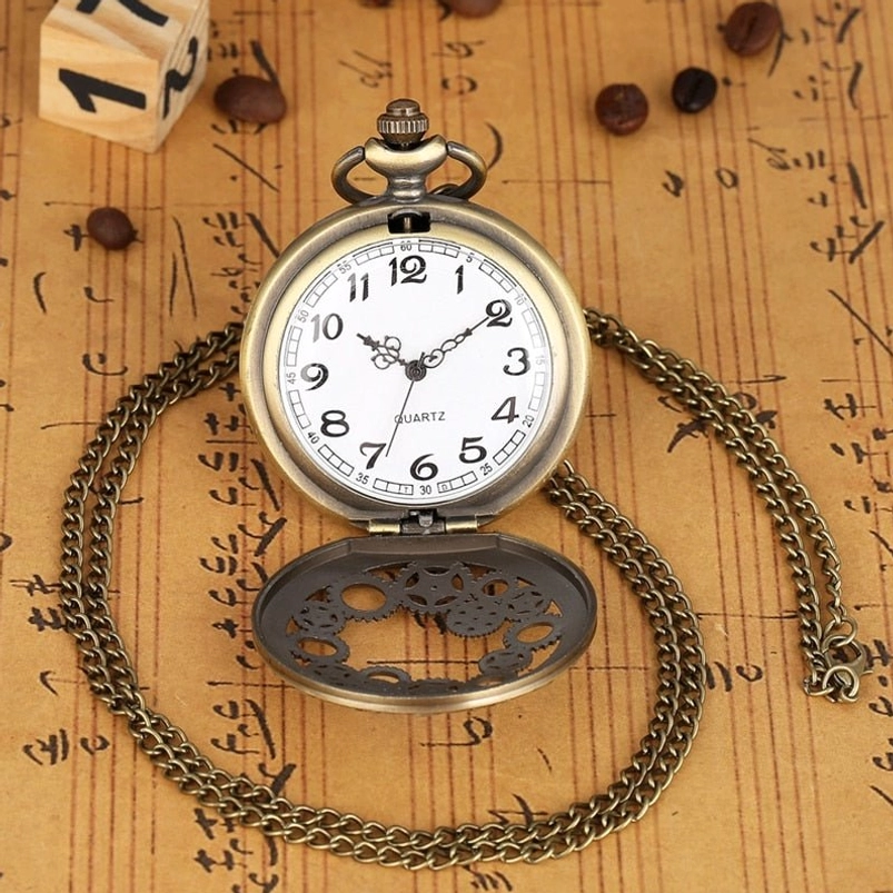 Flip cover steampunk pocket watch flat lay with bronze frame, white Arabic numeral dial, hollow gear engraved flip cover, and long metal chain on vintage paper backdrop