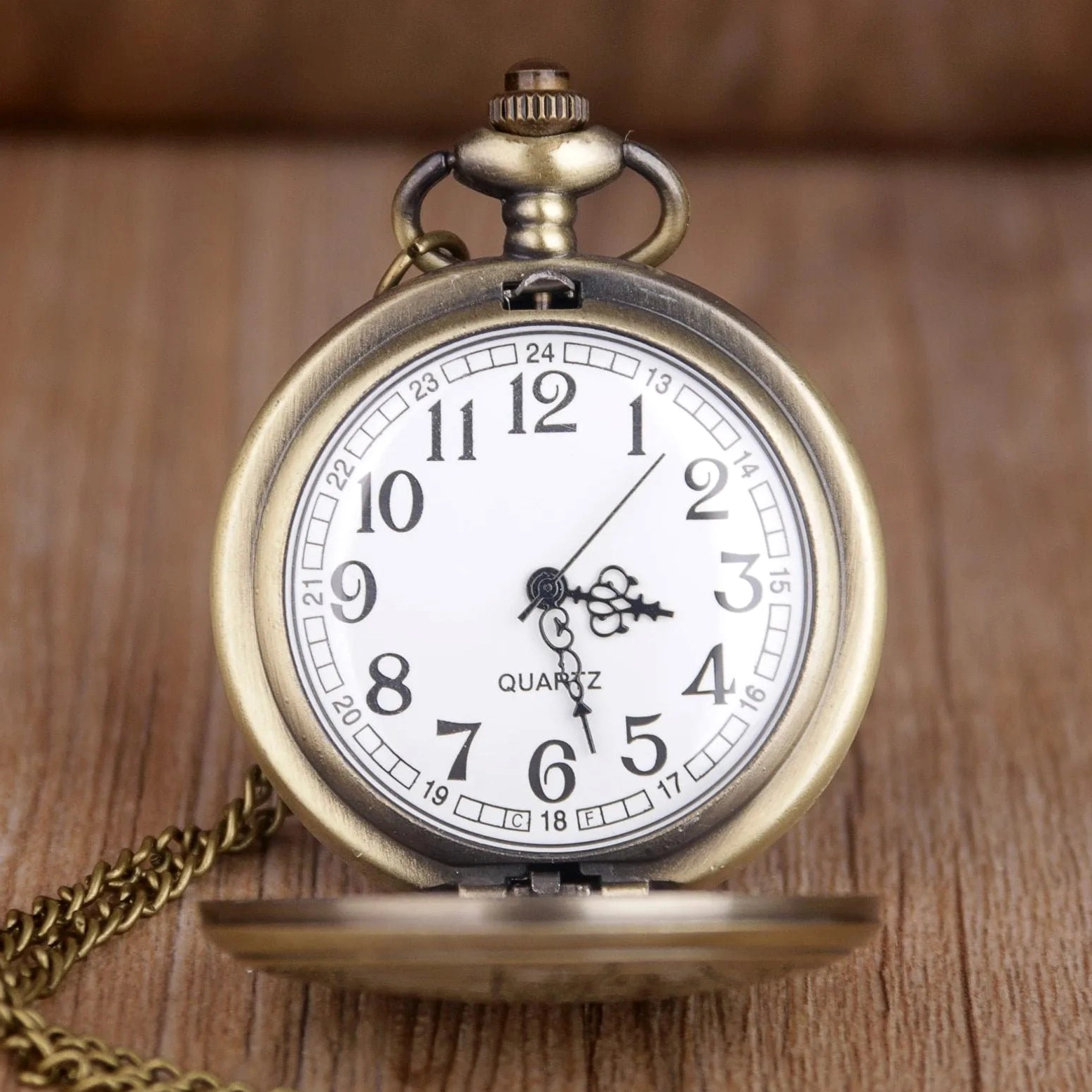Vintage steampunk pocket watch with flip cover open displaying white dial with black Arabic numerals, bronze frame, and precision quartz movement