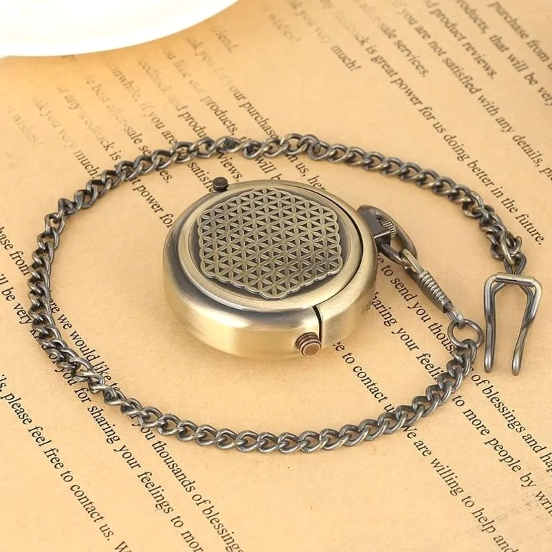 Top-down view of steampunk mechanical pocket watch with flower of life engraved flip cover and coiled metal chain on vintage paper surface