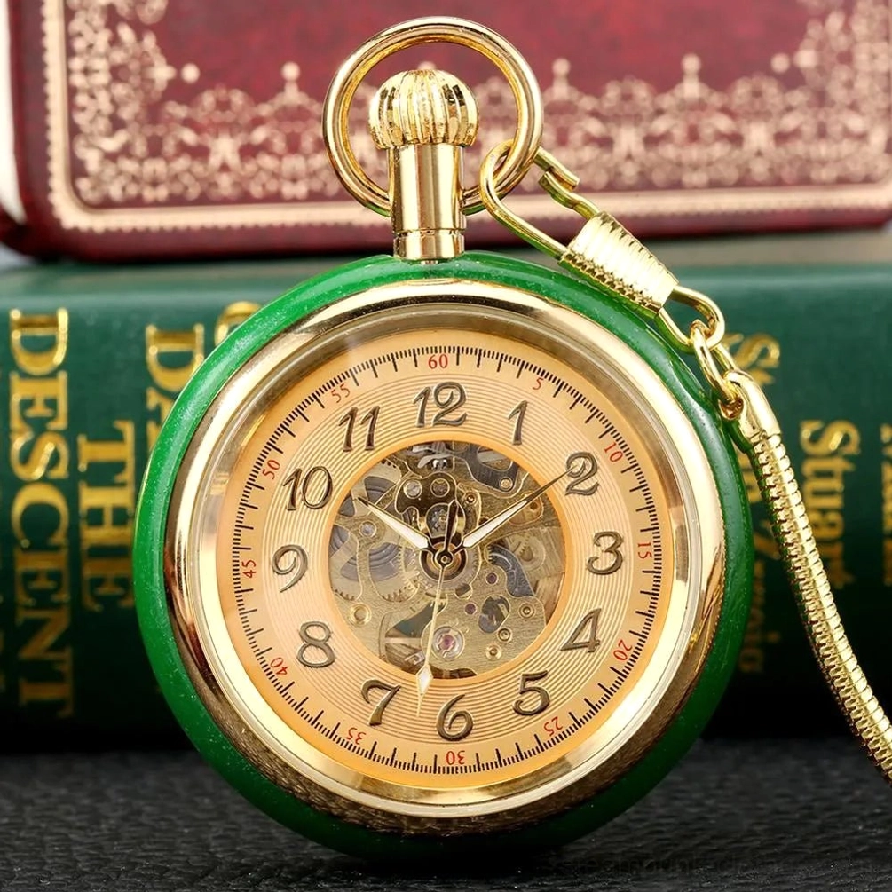 Green steampunk pocket watch with open heart mechanical movement and gold hardware, shown front view against vintage books and leather surface
