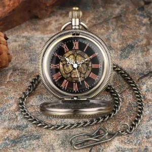 Opened steampunk mechanical pocket watch displaying black dial with red Roman numerals, visible gear movement, bronze case, and attached metal curb chain on stone desktop