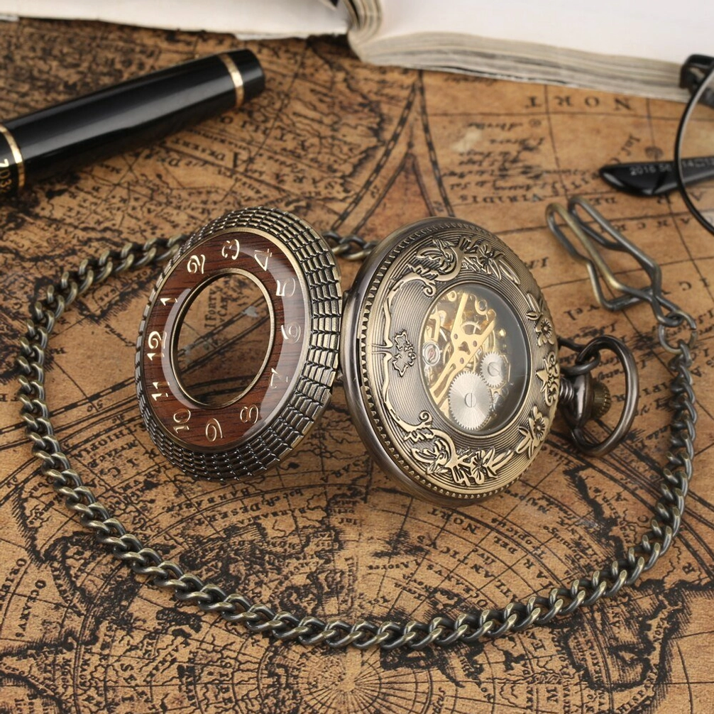 Two steampunk pocket watches with decorative bronze carved covers displayed in top-down flat lay on vintage map with stationery, showing intricate metal structure and design details