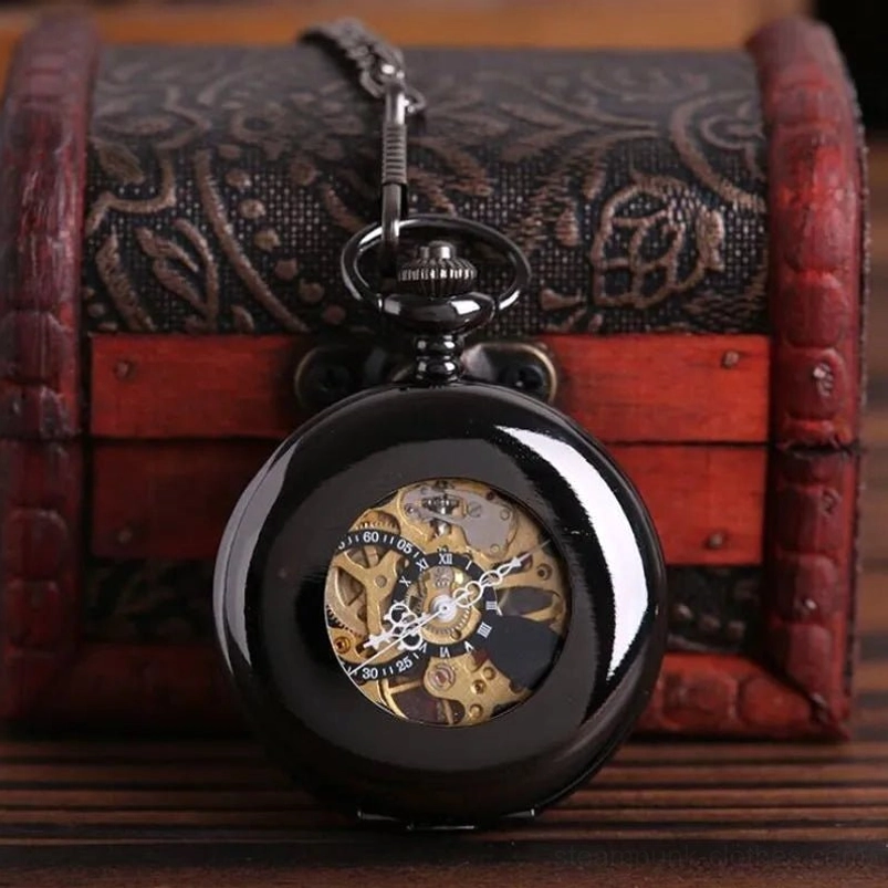 Steampunk mechanical pocket watch with polished black metal case and exposed gold skeleton movement displayed on vintage wooden treasure chest