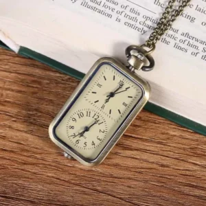 Rectangular steampunk pocket watch with bronze chain shown at oblique angle on wooden desktop next to open vintage book