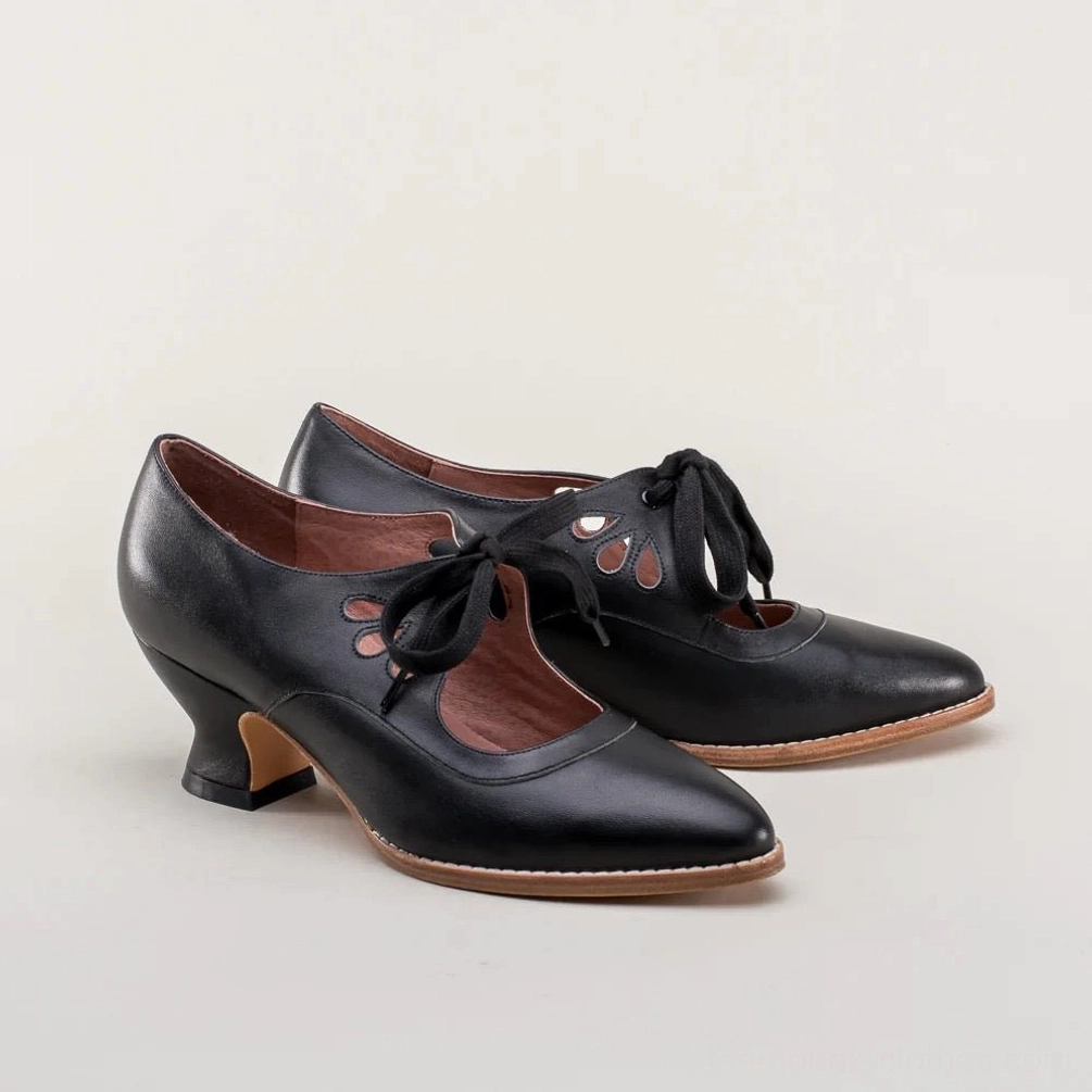 Pair of black steampunk pumps with intricate cutout details and brown leather lining, full product display view