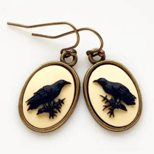 Black raven cameo drop earrings with oxidized bronze frame displayed flat lay on white background, showing straight-on design view and pair detail