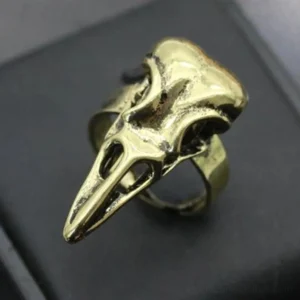 Vintage raven skull steampunk ring with antique gold tone finish, hollow carved design showing intricate bird skull details, front-top close-up view on black leather jewelry display pad