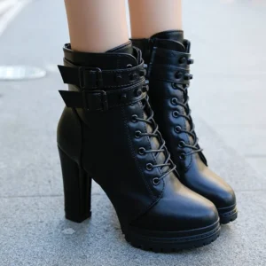 Black steampunk rider lace-up ankle boots with adjustable buckle straps and block heel platform, front close-up view on female model