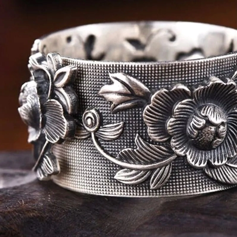 Close-up detail of steampunk ring relief carving featuring intricate floral pattern and grid-textured band surface on polished stone