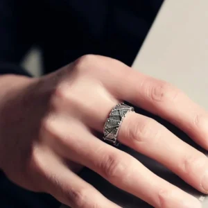 Close-up side view of steampunk ring worn on male left hand, showing worn metal finish and angular riveted industrial details