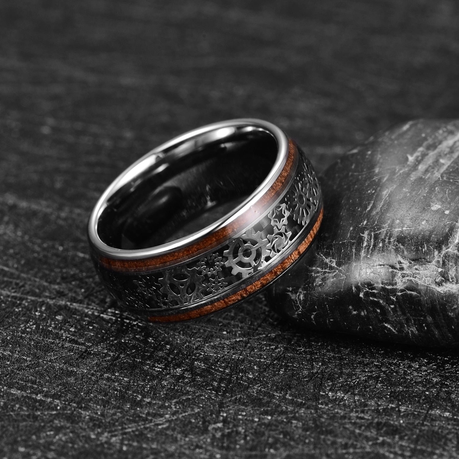 Steampunk tungsten carbide ring side profile displaying smooth polished inner band and detailed mechanical gear patterns, leaning on stone surface