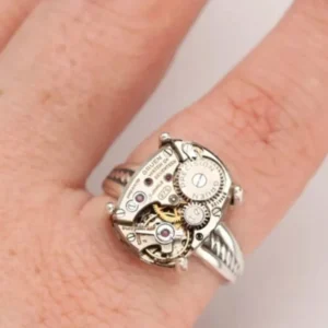Steampunk ring worn on finger front view against white background, showcasing wearing effect and mechanical design details with gears and red stone