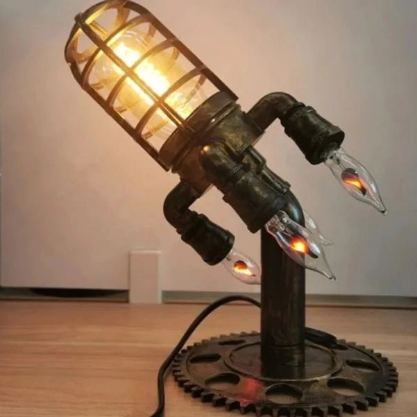 Front view of vintage steampunk rocket lamp with matte black metal, warm lit Edison filament bulb, and mechanical gear base on minimalist wooden desktop