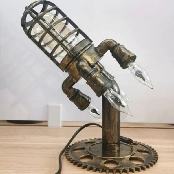 Top oblique angle of steampunk rocket desk lamp showing bronze metal finish, unlit cage shade design, and intricate gear base mechanism