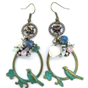 Grey flower steampunk loop earrings featuring verdigris bronze hoop, gear charm, white rose flower, blue opal bead, and pink gemstone accents on white background