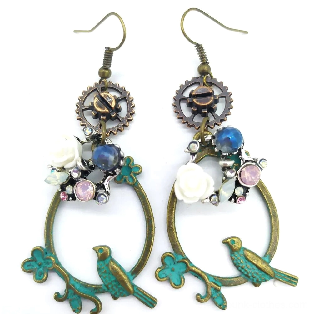 Grey flower steampunk loop earrings featuring verdigris bronze hoop, gear charm, white rose flower, blue opal bead, and pink gemstone accents on white background