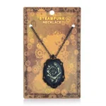 Black filigree steampunk rose cameo necklace with bronze rose motif, displayed on gear-patterned packaging card in retail presentation, showcasing Victorian gothic pendant design