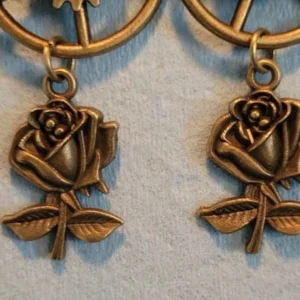 Close-up detail of steampunk rose earring showing intricately carved bronze rose pendant with leaf details