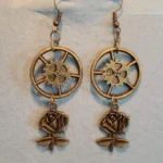 Steampunk rose gear drop earrings in bronze with hollow gear wheels and 3D rose charms, flat lay front view