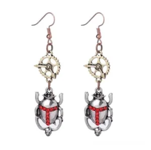 Steampunk silver scarab beetle drop earrings with red rhinestone cross detail, flat lay product photography