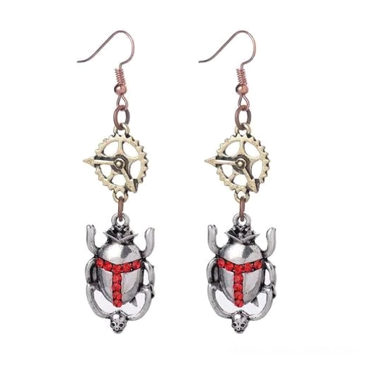 Steampunk silver scarab beetle drop earrings with red rhinestone cross detail, flat lay product photography