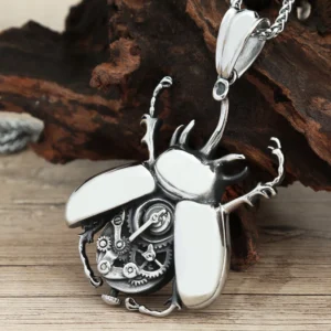 Steampunk scarab beetle pendant necklace with exposed gears and polished wing panels, antiqued silver finish on wooden table with dry wood backdrop