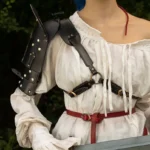 Female model with vibrant blue hair wearing steampunk black leather shoulder armor with silver rivets, paired with off-shoulder white linen blouse, front-left angle outdoor forest setting