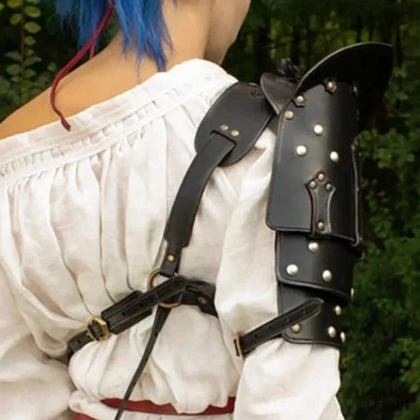 Rear view of steampunk shoulder armor on model with blue hair, showing leather cross-body strap system and adjustable fasteners coordinated with red waist belt in outdoor woodland