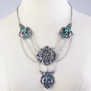 Steampunk layered silver-toned necklace with emerald green crystals and vintage ship wheel engravings, displayed on white mannequin