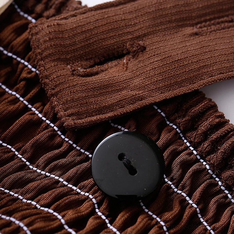Fabric and closure detail showing corduroy texture, shirred elastic seams, and decorative black button accent